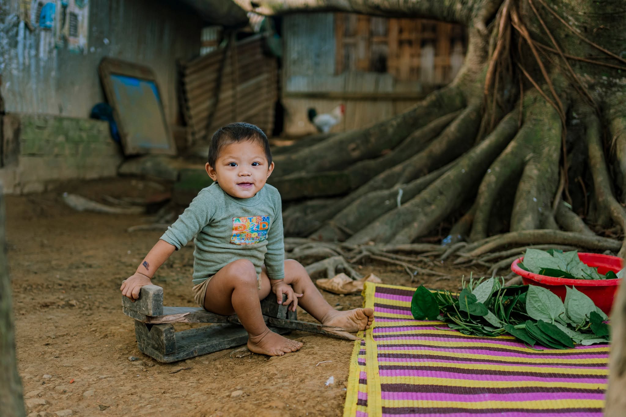 Smiling child seated near betel leaves in a rural village