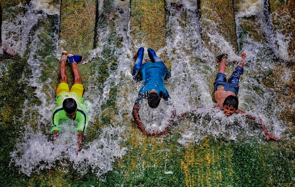 Children sliding down a water spillway on a summer day